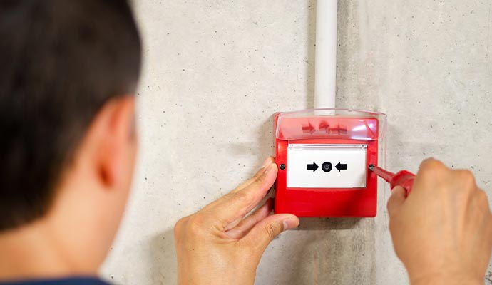 Person performing fire alarm maintenance with a screwdriver