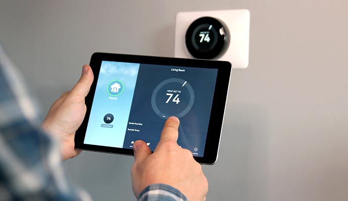 a person using tablet to control smart thermostat