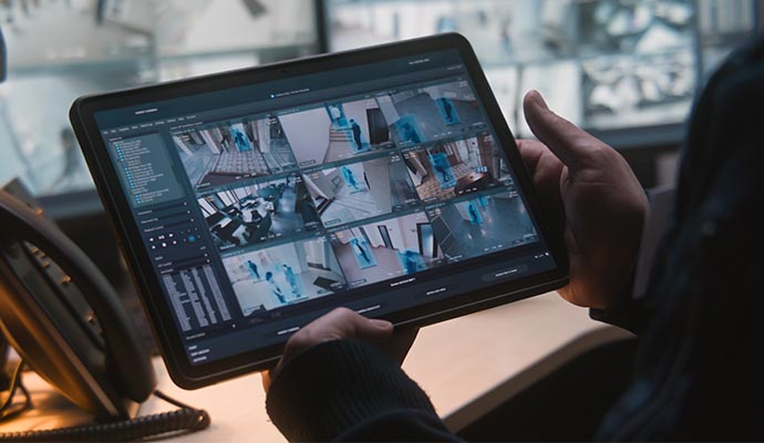 a person monitoring the security cameras of a business using their tablet