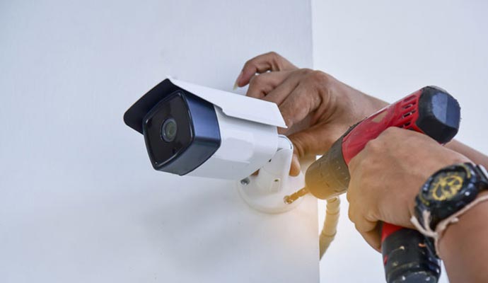 Person installing security camera on wall