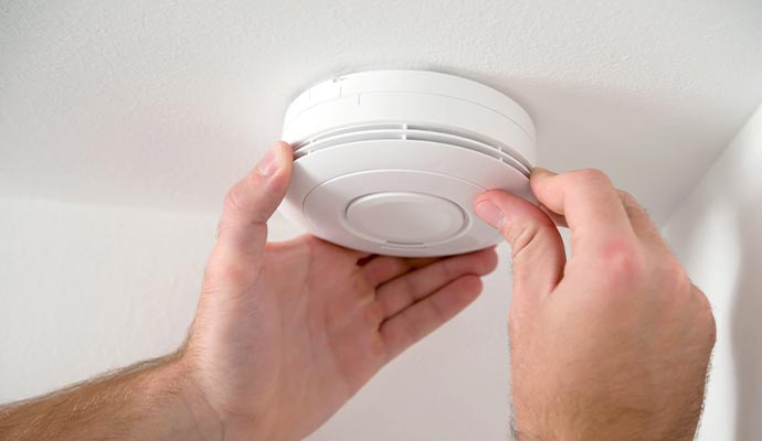 Technician installing a carbon monoxide detector for safety in a residential or commercial setting.